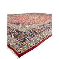 Persian Kashan crimson ground carpet, floral design central medallion surrounded by trailing leafy branches and stylised plant motifs, multi-band border with repeating floral design