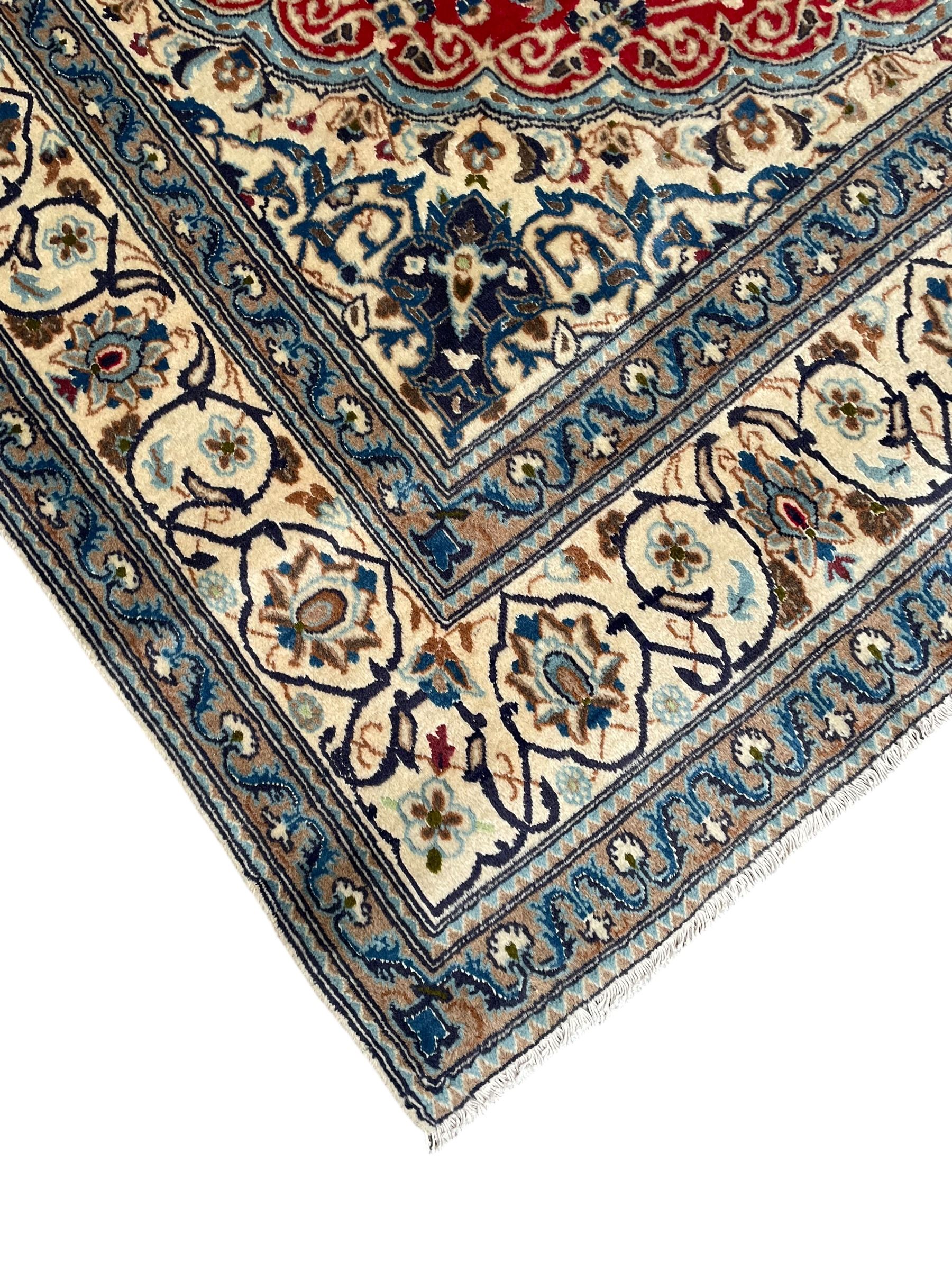 Persian Kashan crimson rug, central cusped medallion surrounded by interlacing branches decorated with leaves and palmettes, ivory ground spandrels and border decorated with scrolling branches and stylised plant motifs, within guard stripes  