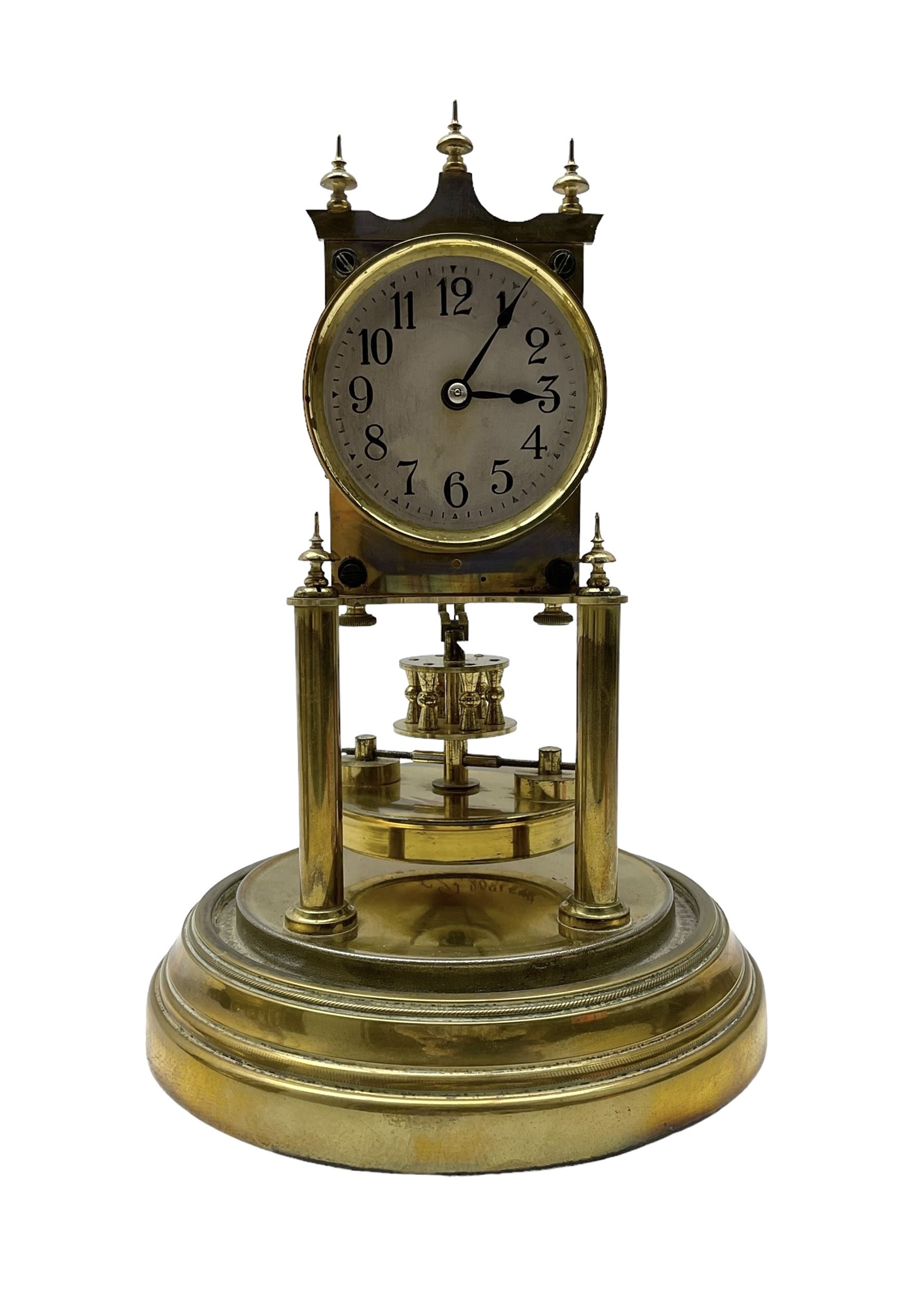 Gustav Becker - German torsion clock, serial No 2086578, on a circular brass base with a glass dome, silvered dial with Arabic numerals and steel spade hands, circular oscillating pendulum, torsion spring intact.