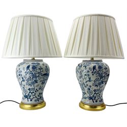 Pair of blue and white table lamps, each of inverted baluster form, decorated with exotic birds, raised upon circular gilt bases, H39cm excluding fitting