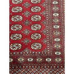 Persian Bokhara rug, red ground and decorated with three rows of Gul motifs, geometric pattern borders with stylised plant motifs