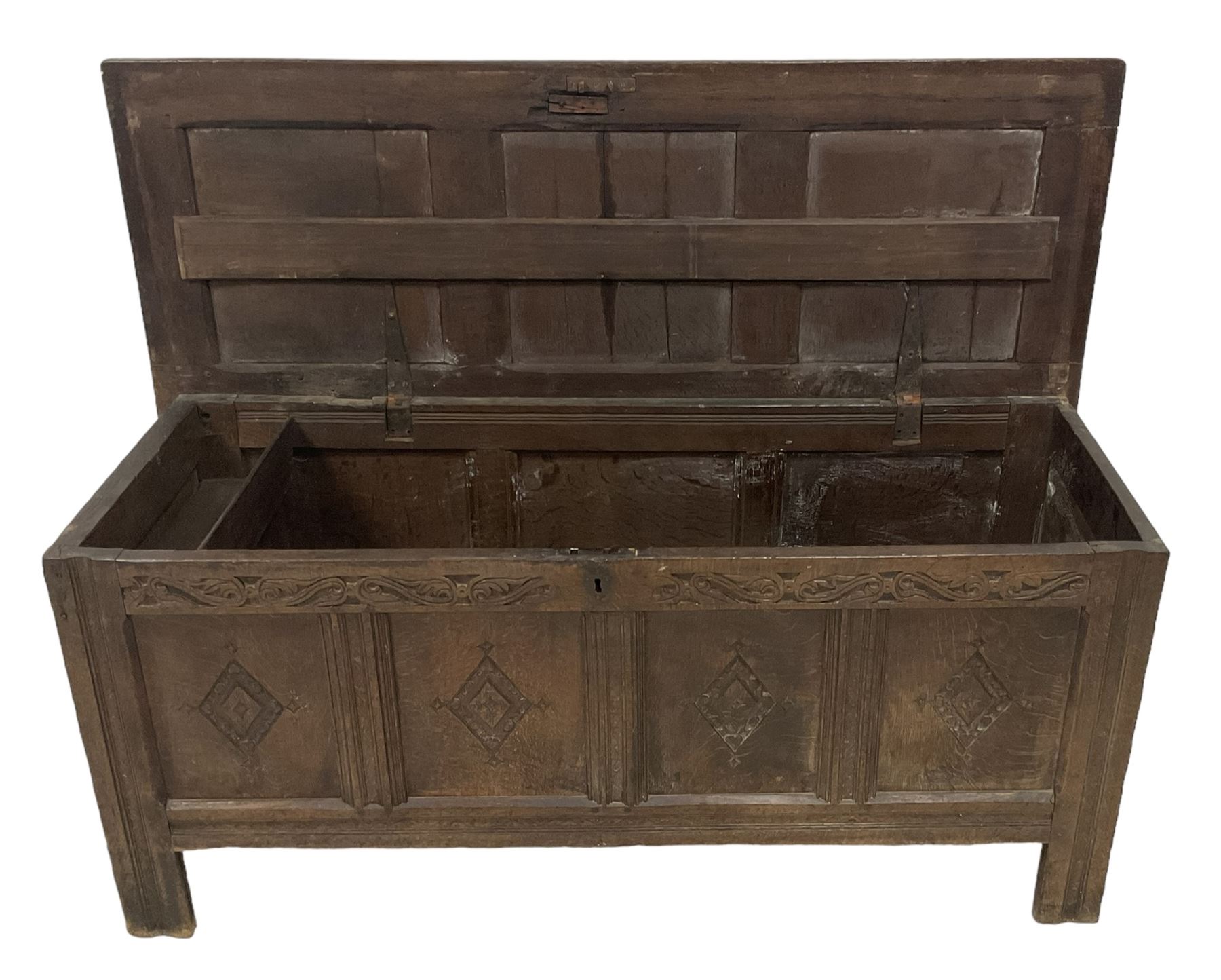 18th century oak coffer or chest, rectangular hinged panelled top with moulded frame enclosing candle box, the frieze carved with foliate S-scrolls over a quadruple panel front decorated with carved lozenges, on stile supports