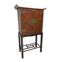 Chinese design bamboo and wood altar cabinet on stand, parquetry lattice-work bamboo, two doors with engraved metal fixtures enclosing drawers and shelf, fitted with slide, the stand pm square supports joined by a series of geometric stretchers