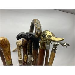 Oak barley twist stick stand, with a collection of walking sticks including examples with carved pommels, horn handles, silver collar etc, together with brass stick stand 