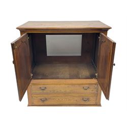 Oak drinks or media cabinet, projecting moulded cornice over two Gothic arch panelled doors on sliding tracks enclosing open storage, two drawers with brass drop handles, on bracket supports