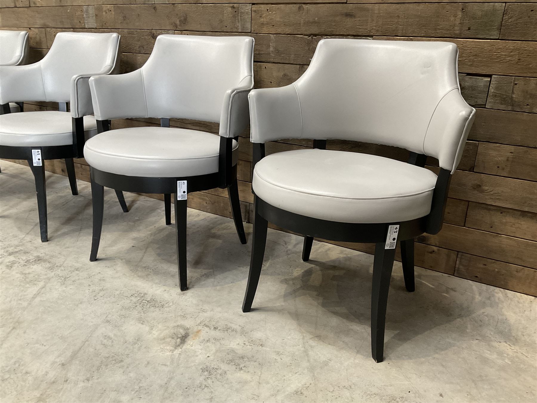 Four ebonised framed tub shaped armchairs, upholstered in grey fabric