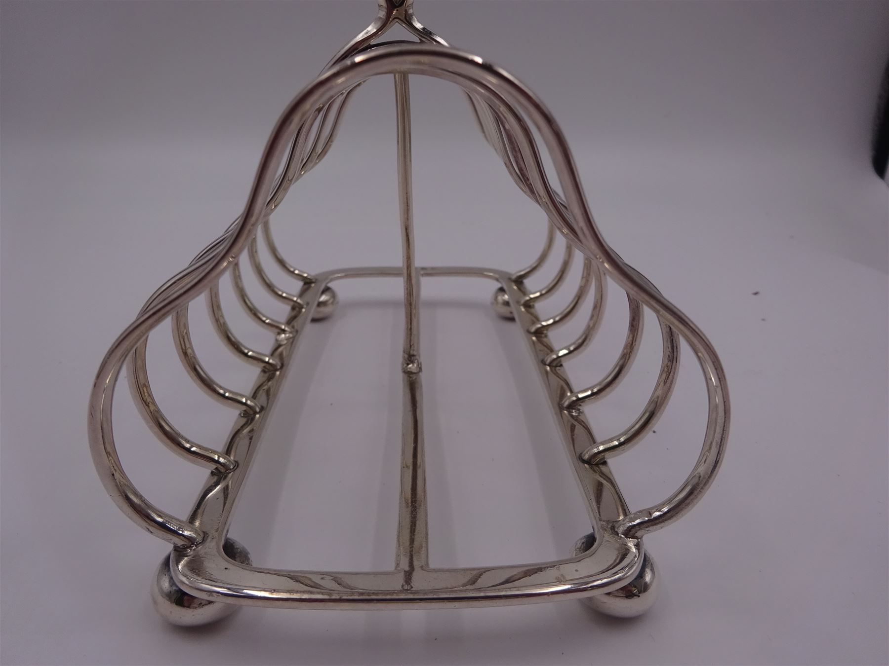 Victorian silver seven bar toast rack, each bar of trilobed form, with similar loop handle and upon four bun feet, hallmarked John Gilbert, Birmingham 1863, H16.5cm