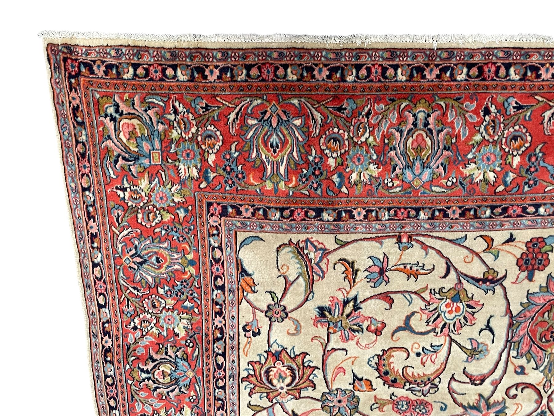 Persian Sarough ivory ground rug, the field decorated with curled leafy branches and palmettes, crimson ground border decorated with further palmettes and floral sprays, within guard stripes 