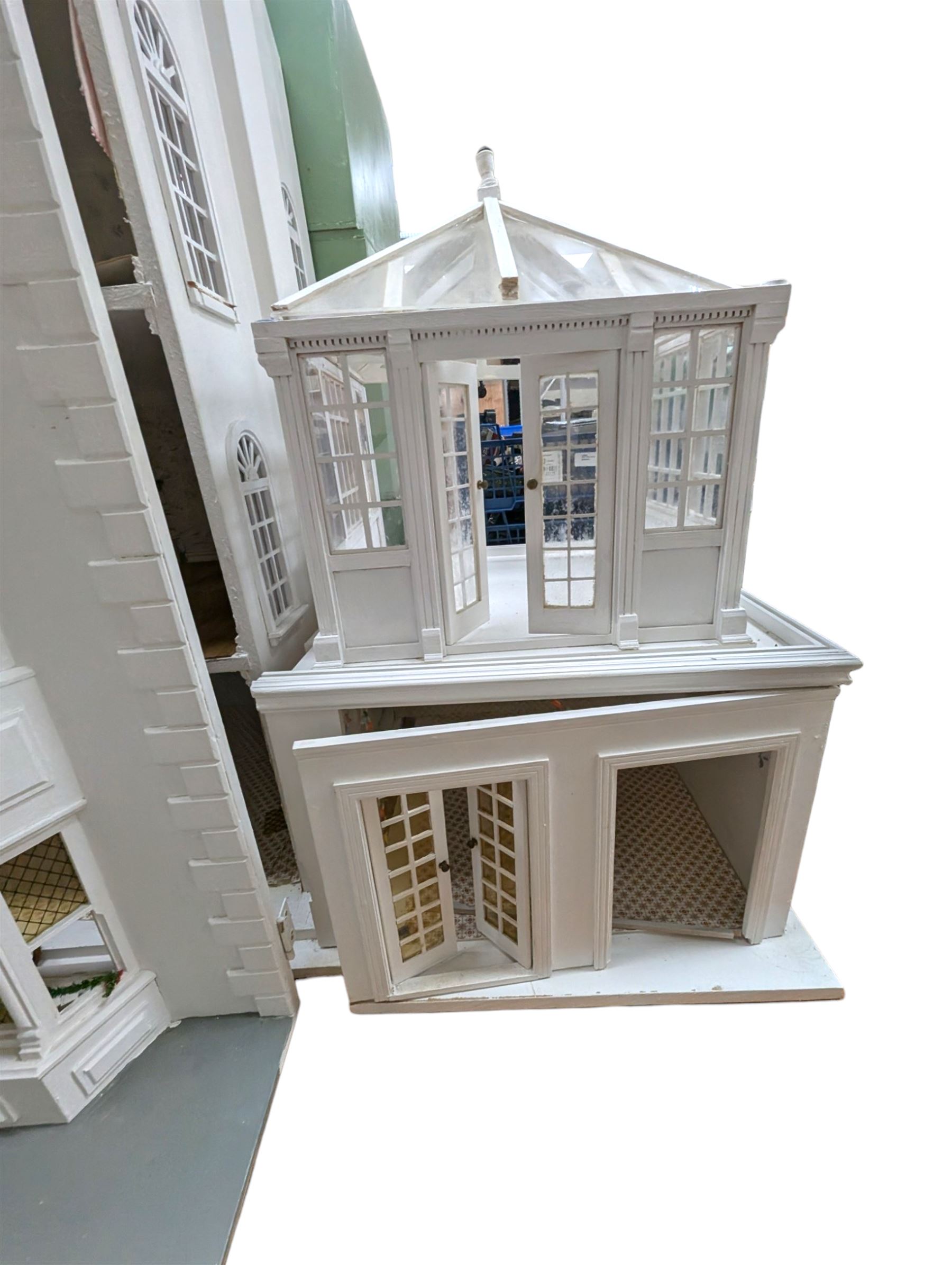 Large three storey modern dolls house, painted white with latticed windows, grey roof and metal fencing, with decorated interior, together with two dolls house garden rooms and two conservatories