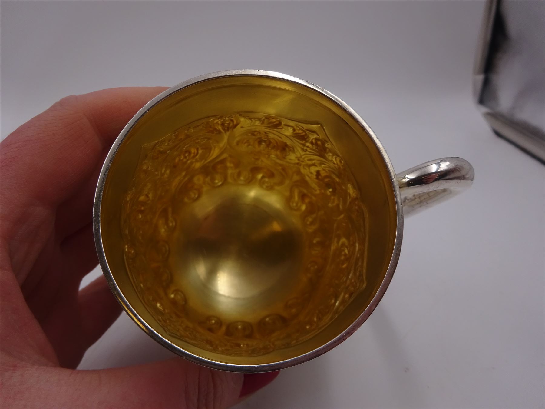 Late Victorian silver christening mug, with C handle and gilt interior, the body profusely embossed with floral and foliate decoration, hallmarked Atkin Brothers, Sheffield 1897, H10cm