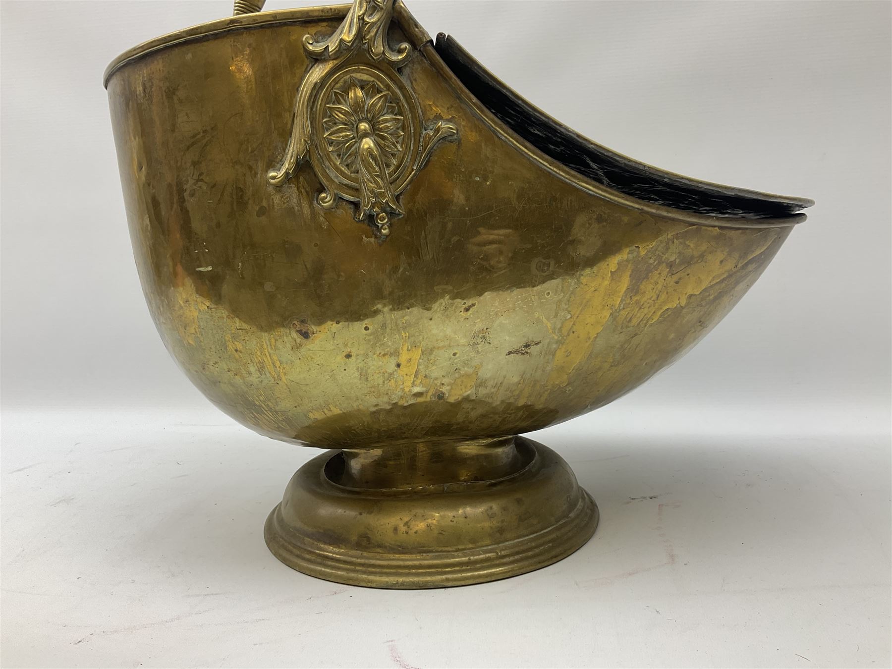 Victorian brass helmet shaped coal scuttle with embossed decoration and turned wooden handle and shovel, H49cm