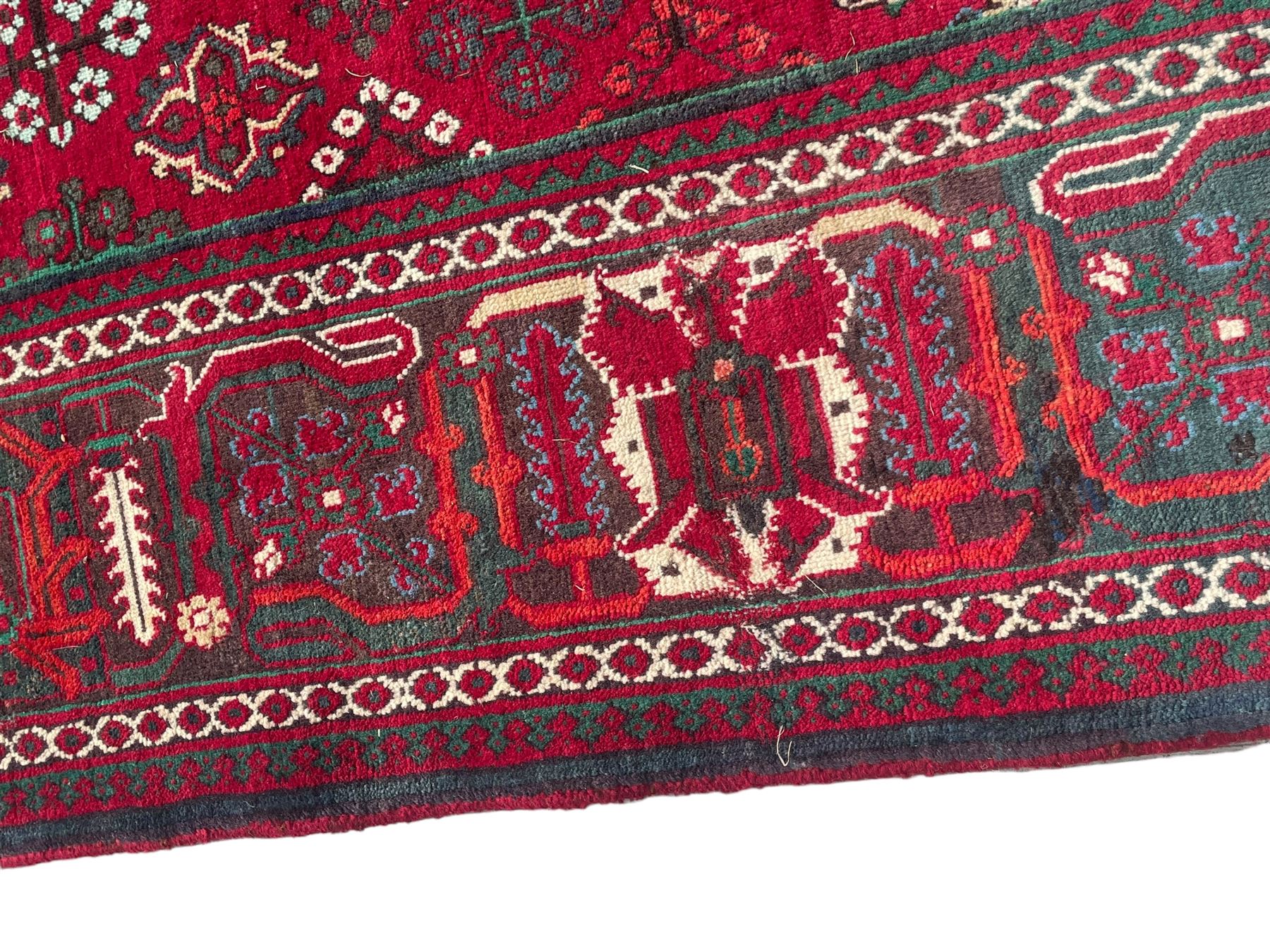 Persian Meymeh red ground rug, stepped lozenge medallion and spandrels, decorated all over with tree of life motifs, the main border decorated with repeating stylised plant motifs within geometric guard stripes 