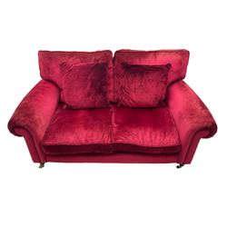 Laura Ashley - two seat sofa upholstered in red velvet fabric, turned mahogany feet with brass castors
