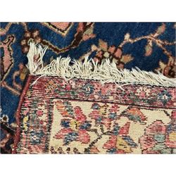 Persian Hamadan ground rug, central medallion design with a salmon pink field, accentuated by navy blue spandrels, surrounded by a stylised floral border in cream and blue tones