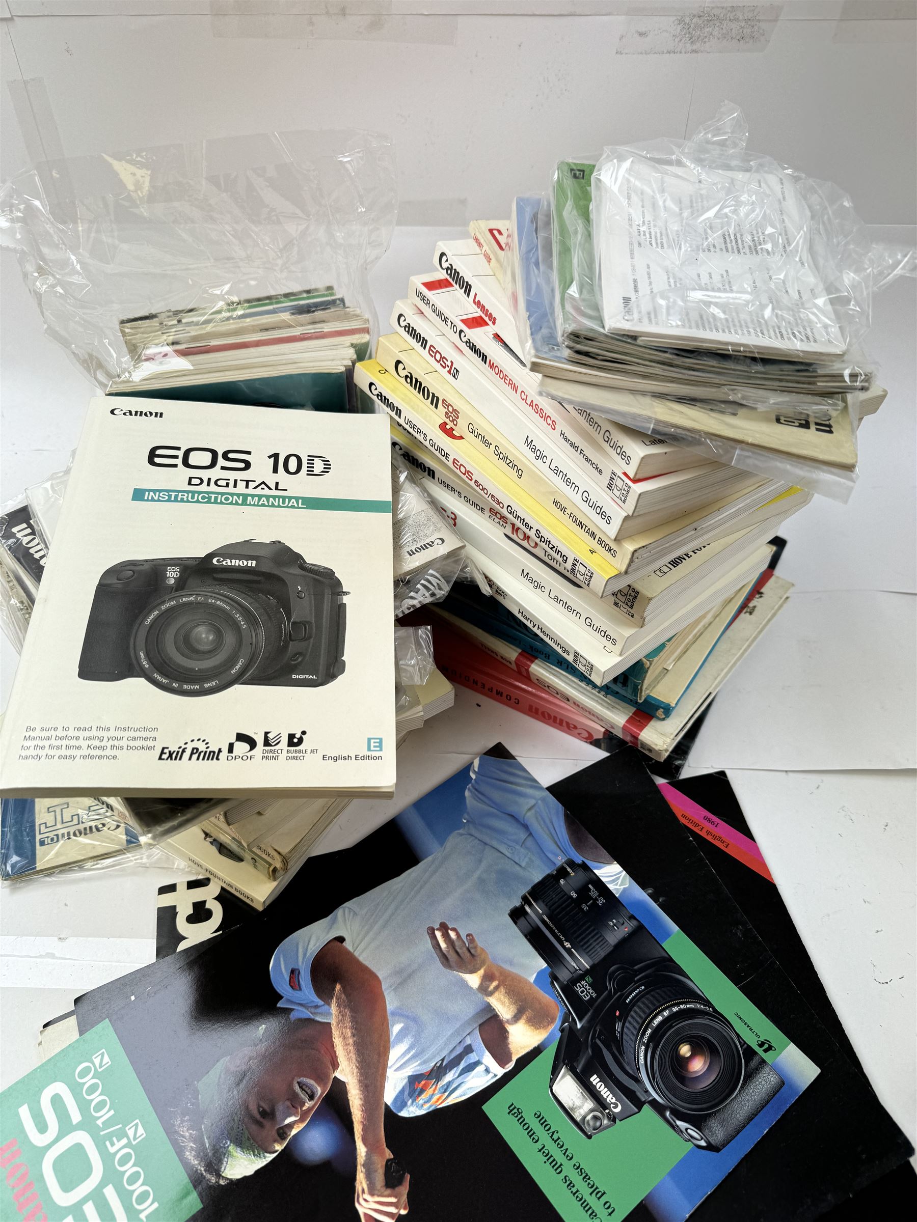 Large collection of Canon camera reference books, brochures, user's guides and instruction manuals, including Canon Compendium by Bob Shell, copies of Lens Wonderland, EOS camera guides, etc 