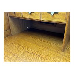 Early 20th century oak tambour roll-top desk, the top with fitted interior including drawers, pigeonholes and compartments, the twin pedestals fitted with four drawers with carved handles, supported by plinth base 