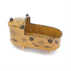 Earthenware slipware rocking cradle, decorated with flowers and foliage motifs, upon a yel...