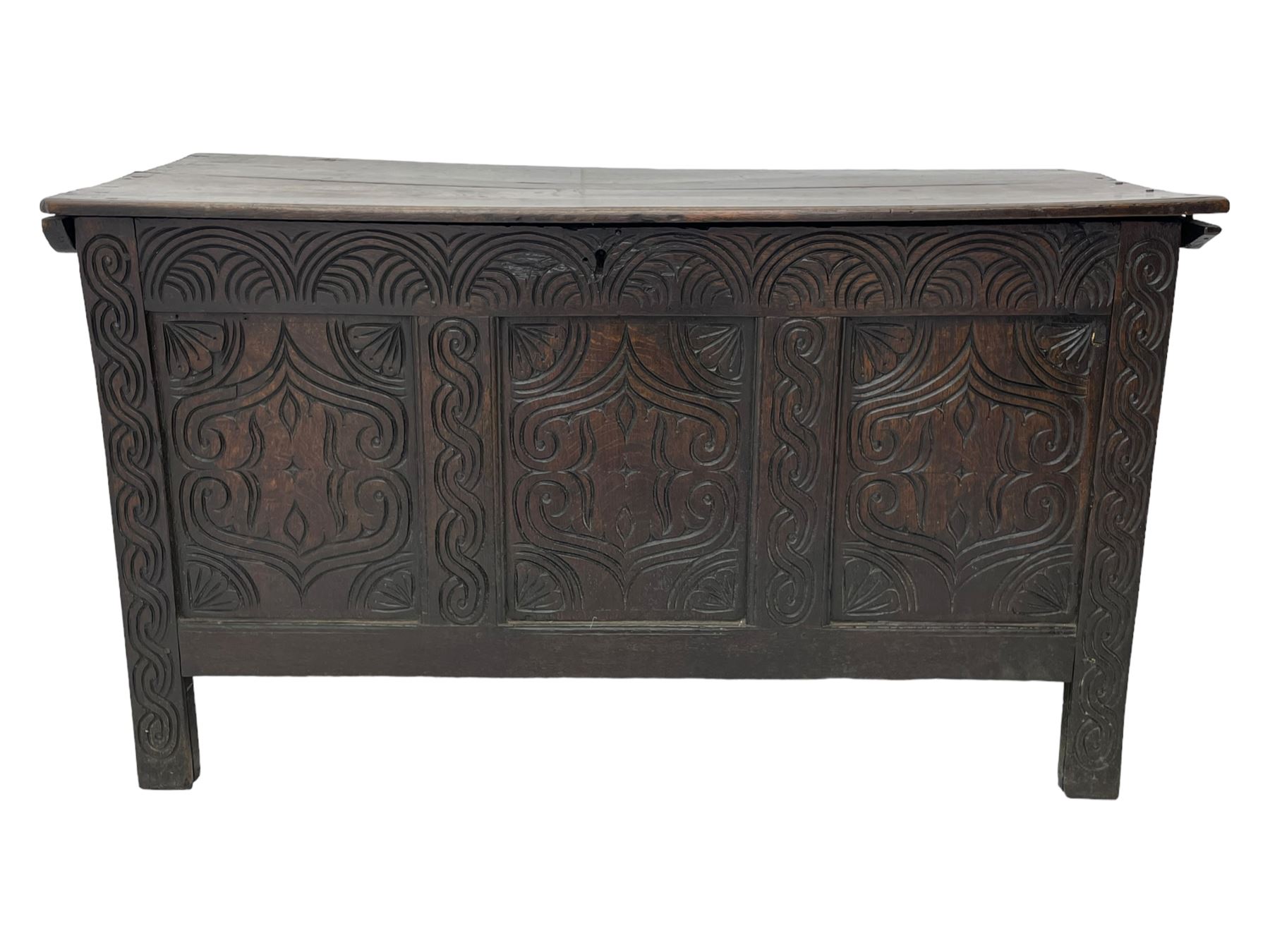 18th century oak blanket box, moulded and chip carved hinged lid, lunette carved cresting rail over triple panelled front carved with stylised leaf and scroll decoration, interlocking S-scroll carved upright rails, panelled sides and back, on stile supports 