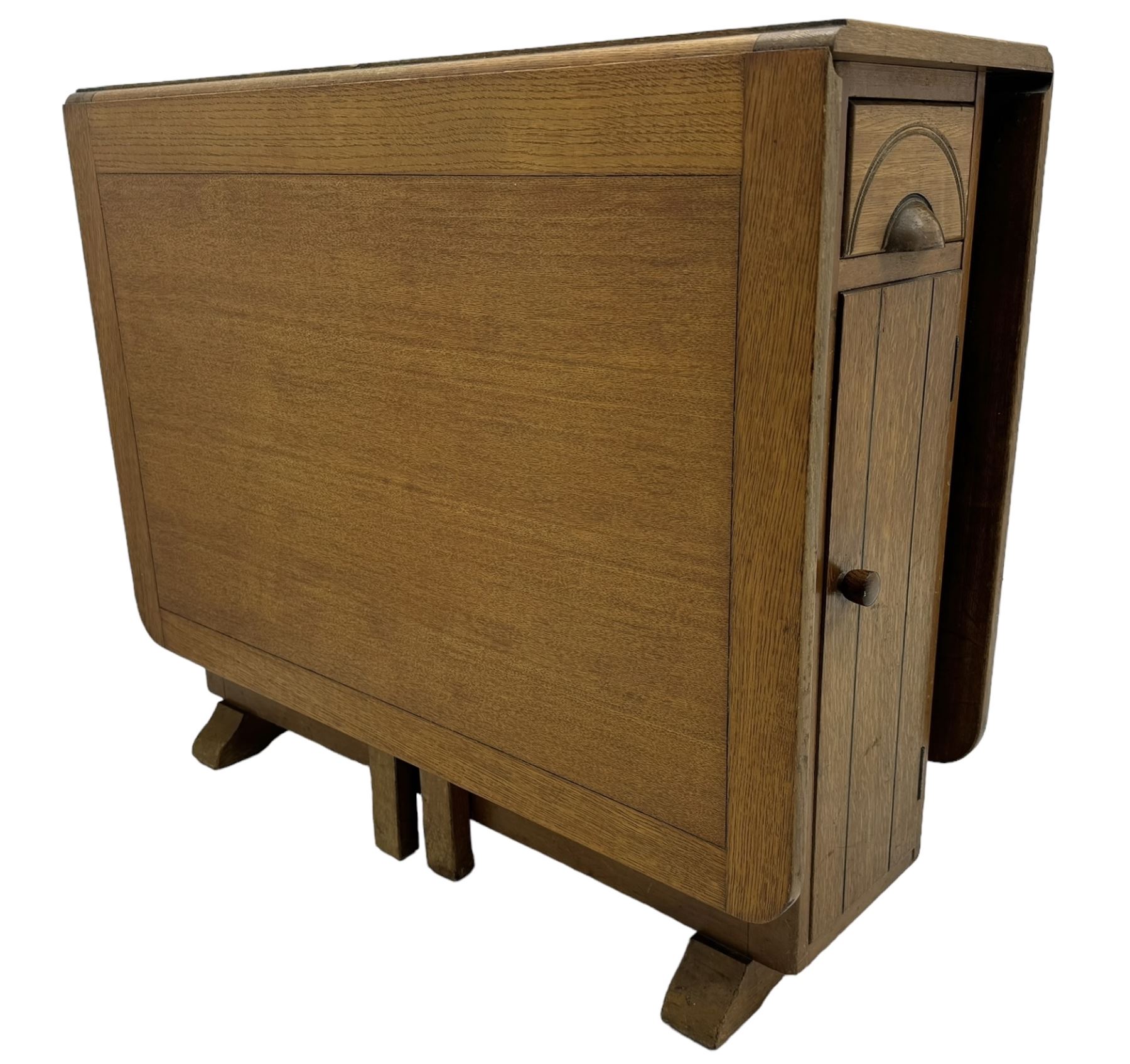 Early 20th century oak drop-leaf table, in the style of Harris Lebus, featuring rectangular top over central pedestal base, with two drawers and two cupboards, on gateleg supports