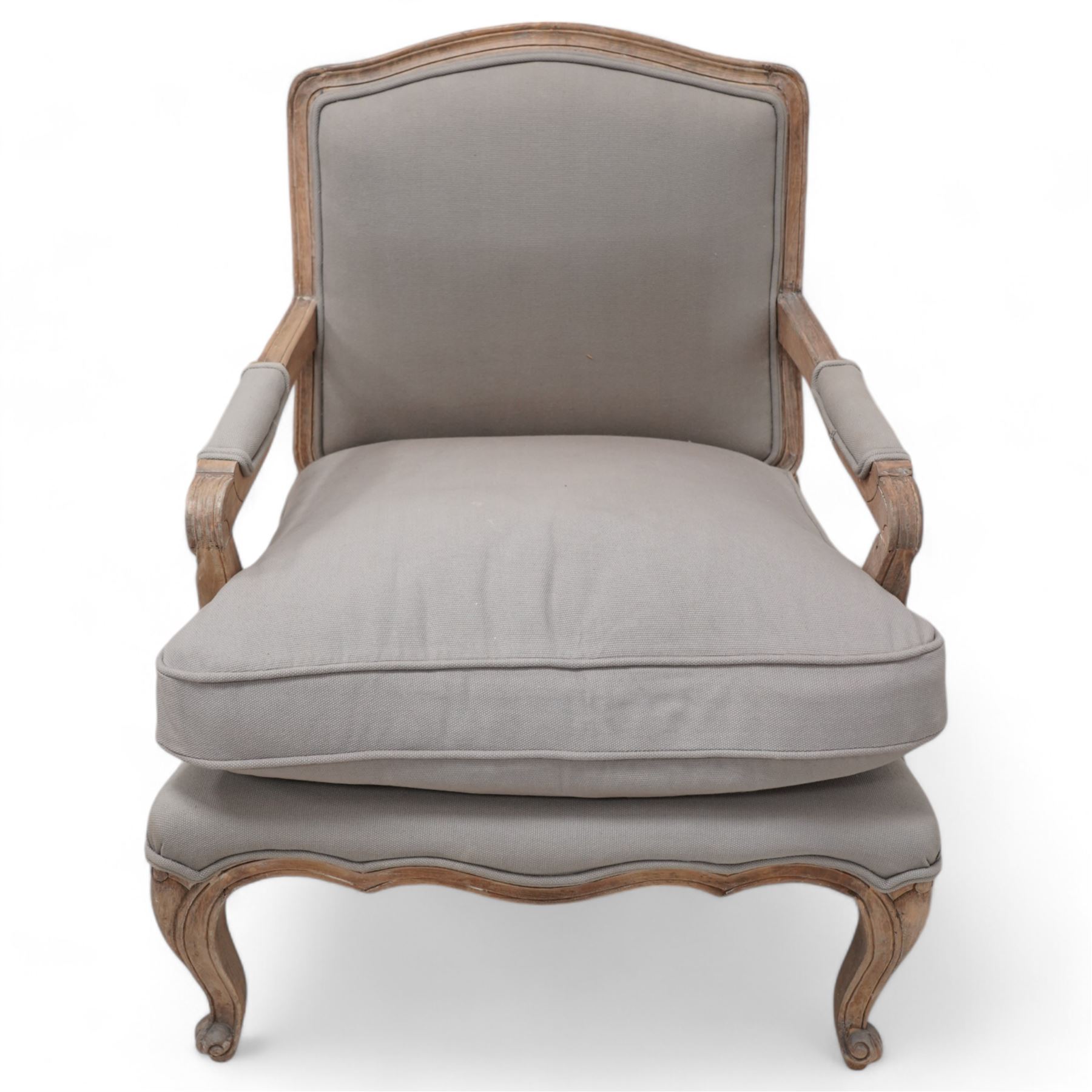 Louis XV design limed hardwood framed open armchair, upholstered in pale taupe fabric with loose seat cushion, raised on cabriole supports with scroll feet