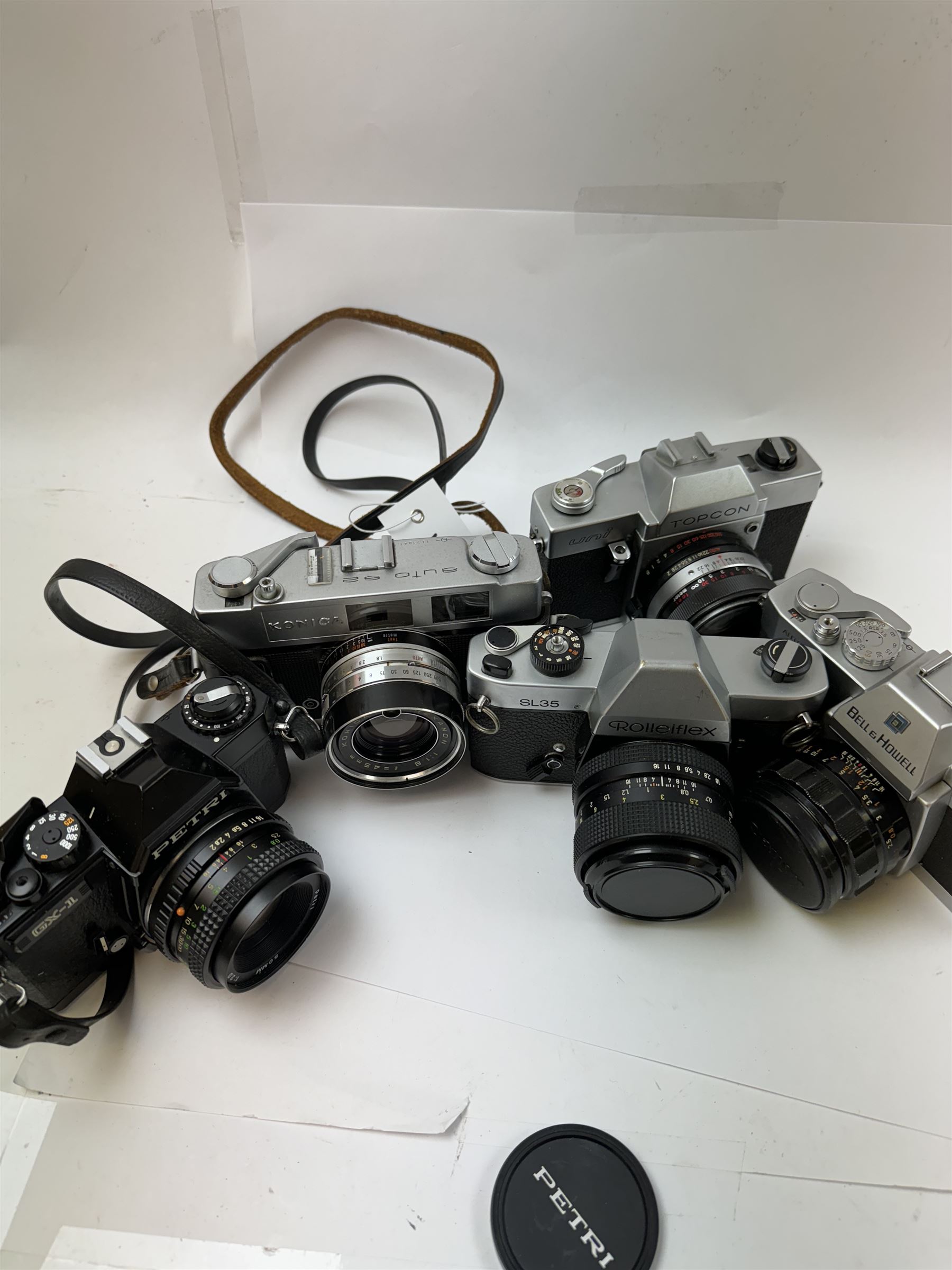 Five SLR cameras, to include Rolleiflex SL35, with a Rollei-HFT Planar 1.8/50 lens serial no. 1246774, Topcon Uni serial no. 5417650, with a Topcor Kogaku UV 1:2 f=53mm lens serial no. 5413035, Bell & Howell Auto35/Reflex Design 237, with a Canon EX 50mm 1:1.8 lens serial no. 92960, Petri GX-1 serial no. 91206945, with a Petri 50mm 1:2.0 lens serial no. 91107428, and a Konica Auto 52 serial no. 1193641, with a Konica Hexanon 1:1.8 f=45mm lens, all in cases 