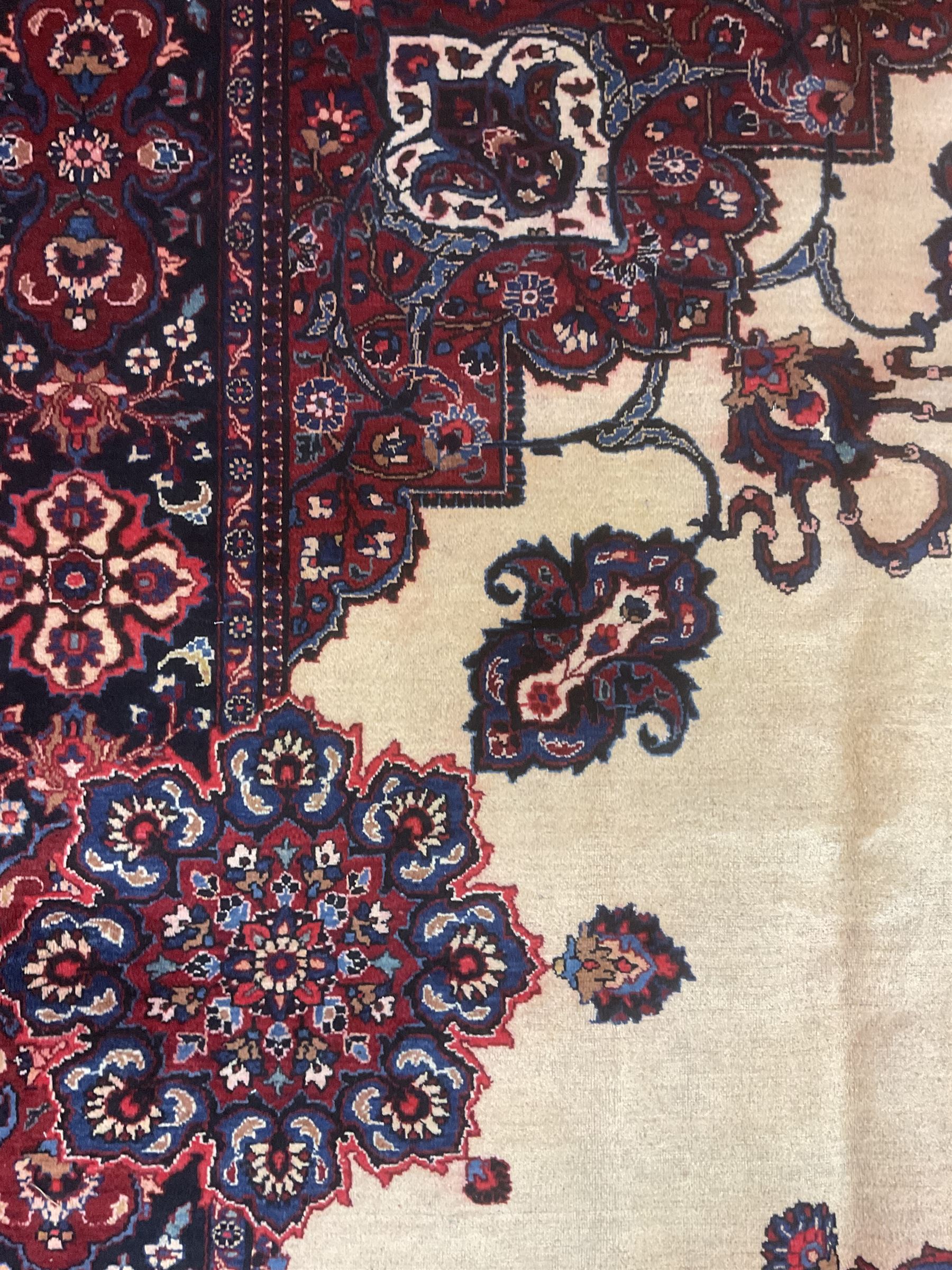 North East Persian Meshed carpet, the field with large central medallion decorated with stylised plant motifs, the field surrounded by panels, medallions and spandrels decorated with floral motifs, indigo ground border with overall floral design 