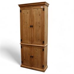 Tall 20th century stained pine cupboard, projecting cornice over four panelled cupboard doors, enclosing shelves, on skirted base, with iron fittings and handles