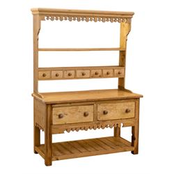 Early to mid-19th century pine cottage dresser, projecting cornice over fretwork frieze, the rack fitted with two shelves over a bank of seven small spice drawers, the base comprising two drawers above an open shelved section