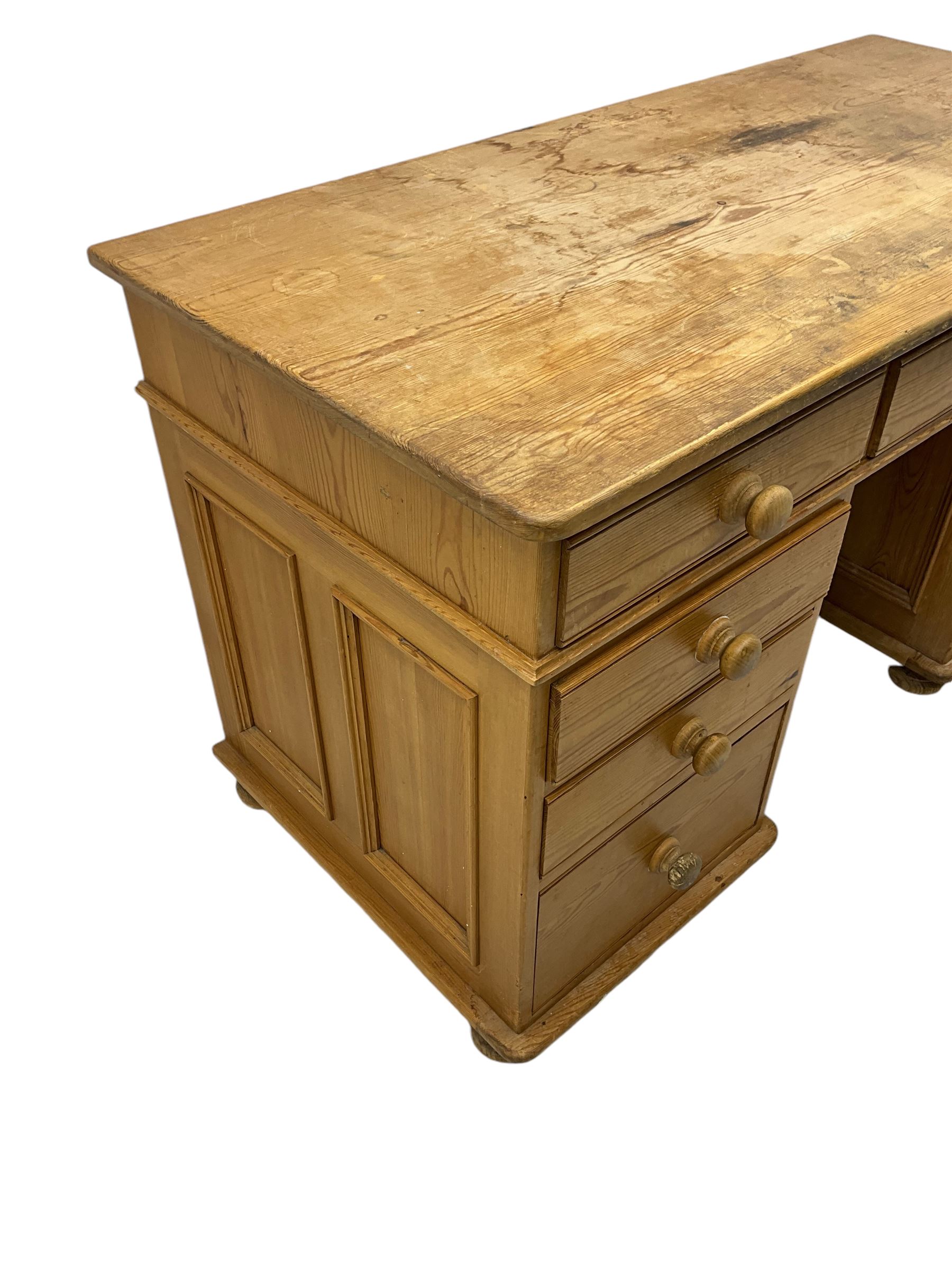 Waxed pine twin pedestal desk, rectangular top over nine drawers, on compressed bun feet 