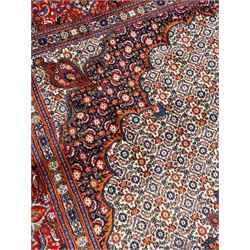 Persian Bidjar ivory and indigo ground rug, large central rosette medallion surrounded by floral herati motifs, crimson ground border decorated with repeating palmettes, within guard stripes decorated with small flower head motifs 