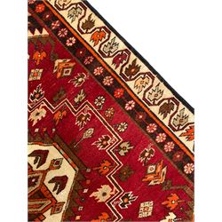 Persian crimson ground rug, the field decorated with three medallions within stepped borders, decorated all over with small stylised plant motifs, trailing flower head outer band and floral pattern border 