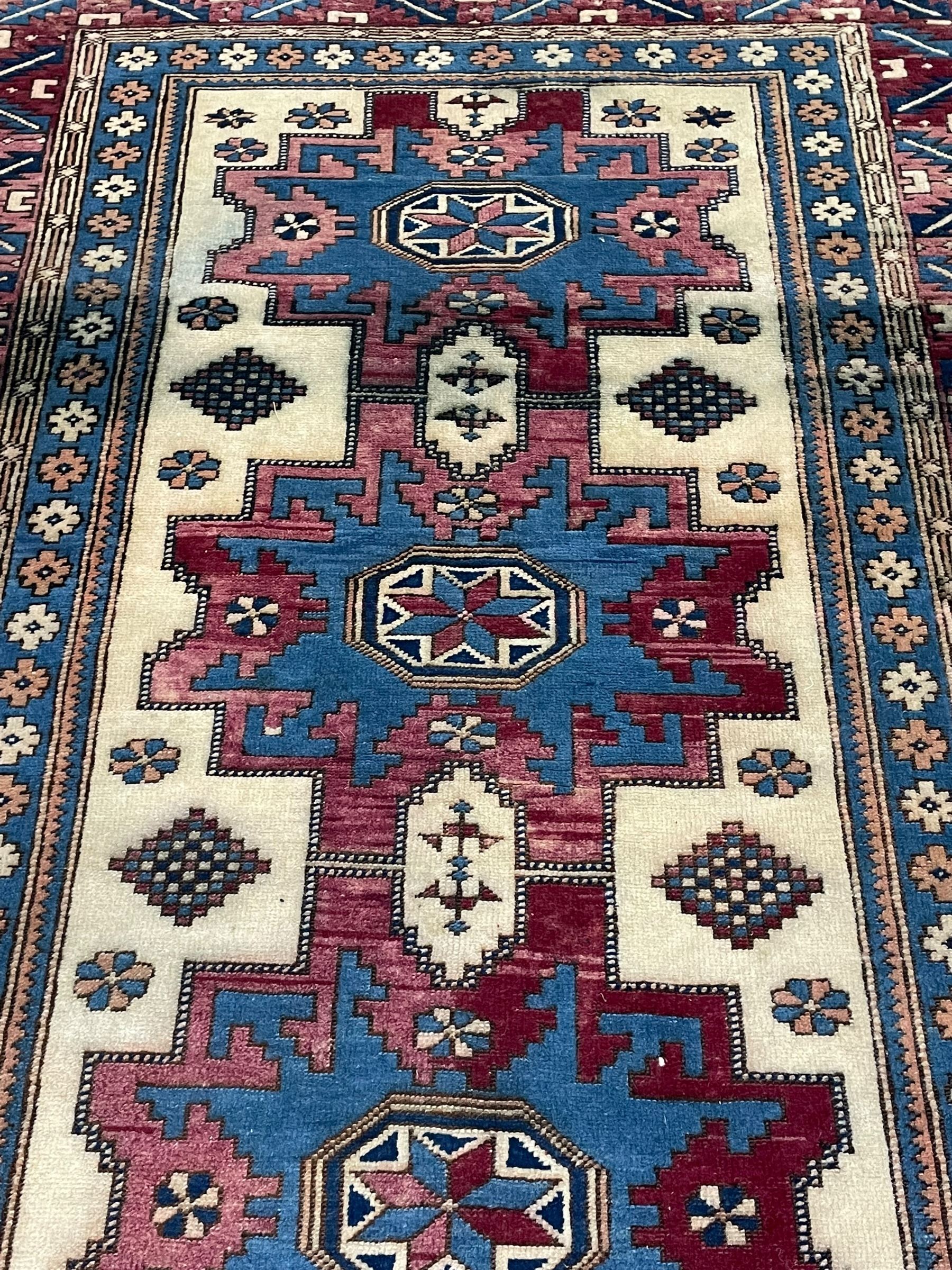 Turkish camel ground rug, three medallions surrounded by geometric motifs, the border decorated with stylised leaf motifs