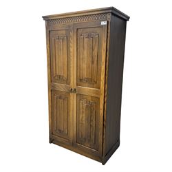 Jacobean design oak double wardrobe, projecting cornice over Gothic arched tracery carved frieze, twin panelled doors with linenfold relief carved detailing, on plinth base