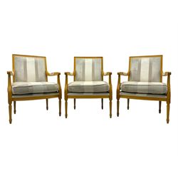 Three mid-20th century beechwood fauteuil armchairs, upholstered backrest and seat in cream stripe fabric, padded armrests with scroll detail, on tapered fluted supports with carved floral rosette blocks