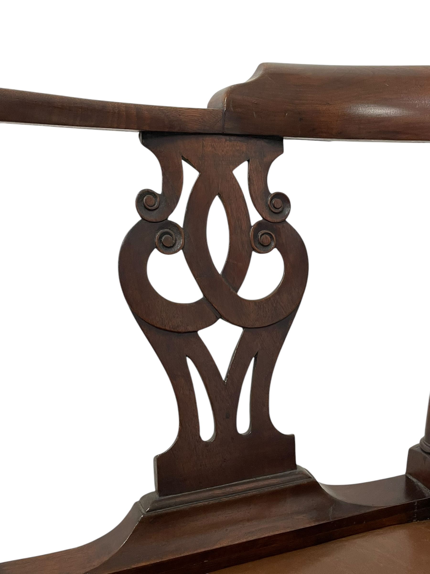 George III mahogany corner elbow chair, curved back rest and shaped arms with scroll carved terminals, on turned supports and pierced scroll carved interlaced splats, drop-in seat upholstered in brown leather, on square supports with inner chamfer and outer moulding 