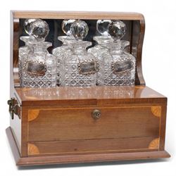 Edwardian walnut and boxwood inlaid tantalus games compendium, having three square section cut glass decanters, with associated silver Brandy, Sherry and Whisky labels, the two hinged doors with Bramah lock, open to reveal a fitted interior with four sherry glasses, over a secret sprung drawer to the base containing a selection of playing cards and cribbage board, L36cm x H32cm 