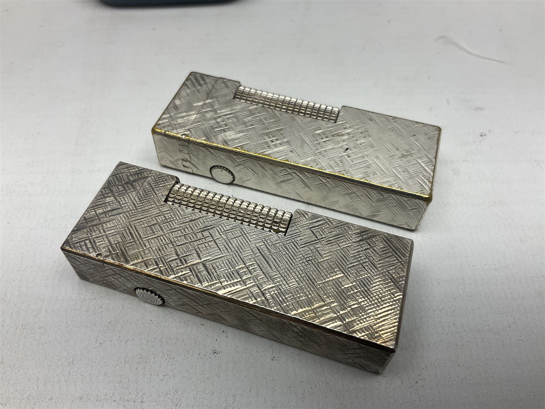 Three Dunhill silver plated lift-arm lighters, of rectangular form with engine turned decoration, marked Dunhill, two with original cases 