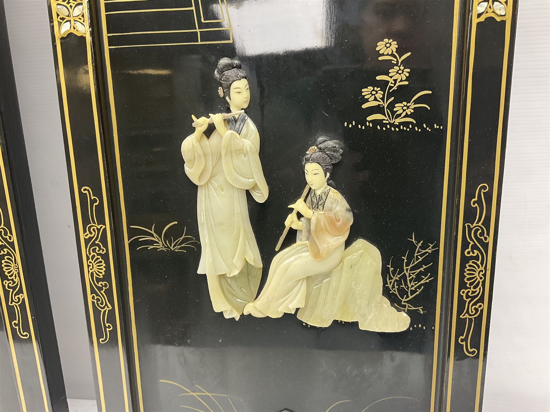 Two 20th century Chinese lacquered wall plaques, decorated in relief with female figures playing instruments beneath a pagoda, within gilt and mother of pearl inlaid borders, H92cm