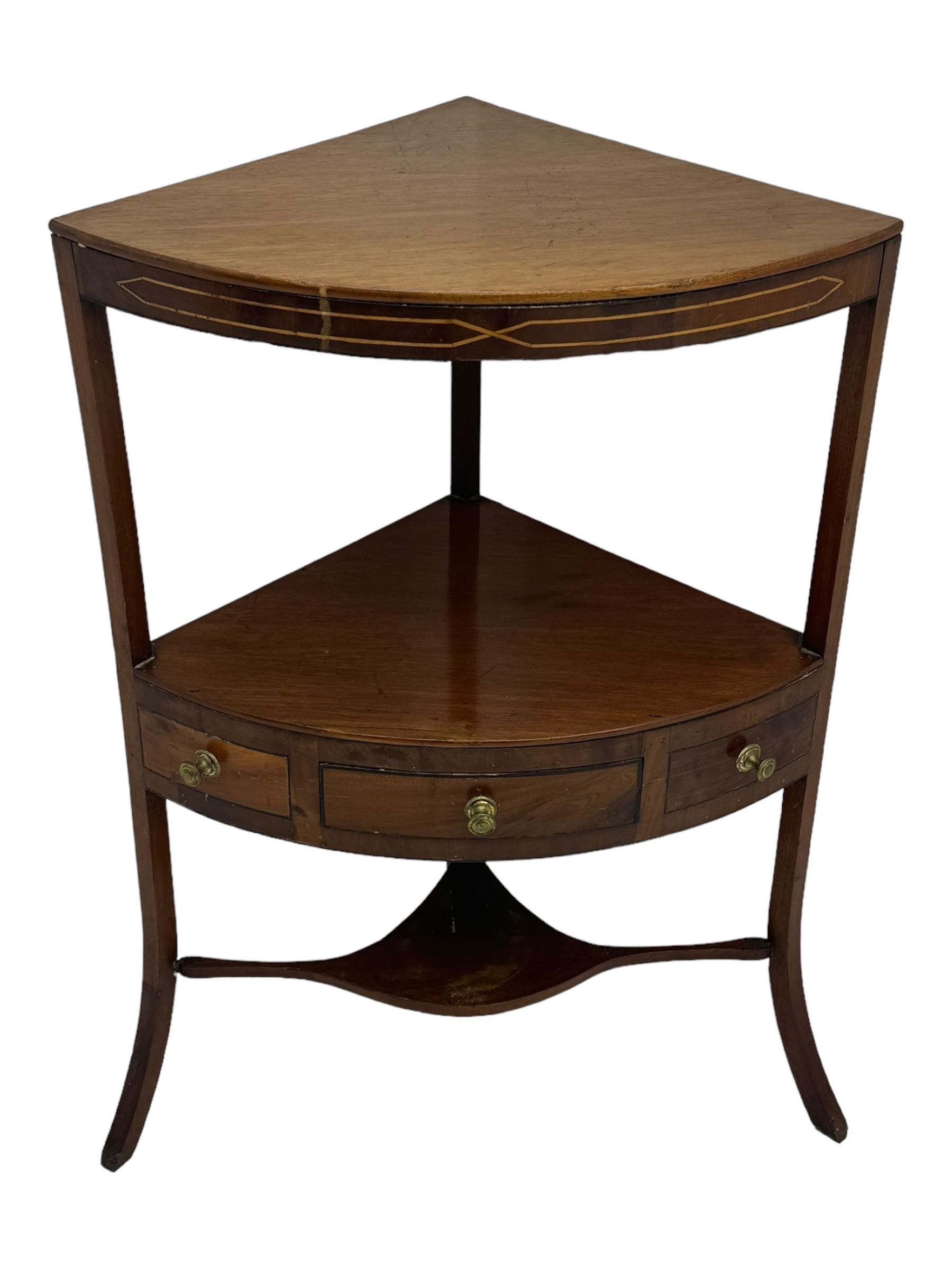 George III mahogany two-tier corner washstand, the inlaid top with geometric border, central drawer flanked by two faux drawers each with brass pull handle, on splayed supports united by shaped under-tier