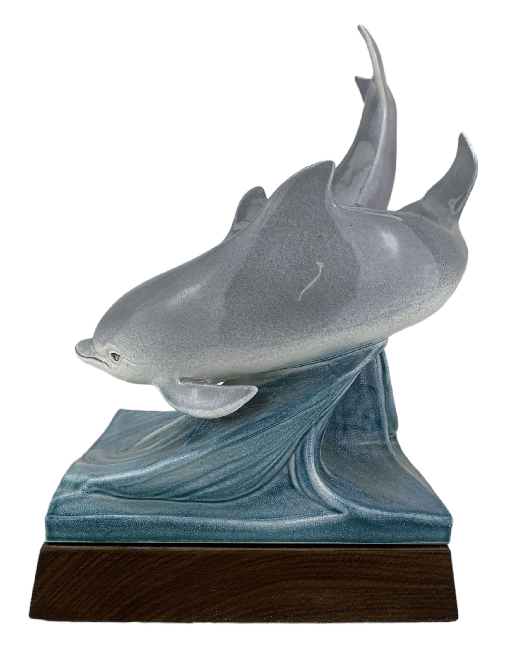 Tony Morris for Poole Pottery, leaping dolphin group, modelled over waves and mounted on a wooden base, H29cm. This model is a duplicate of a sculpture presented to Queen Elizabeth II and the Duke of Edinburgh on their visit to Poole Pottery in 1979, the original cast was destroyed after the production of the duplicate. Provenance: Arnold Smith, Chairman of Pool Potteries Collection