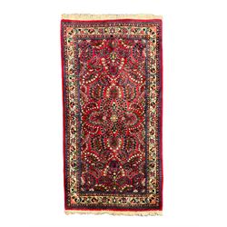 Small Persian red ground rug, the field decorated with an overall floral design, guarded ivory ground border decorated with trailing flower heads and foliage