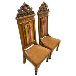 Set of six 20th century Carolean design oak high back chairs, the pediment carved with dragons and central Green Man mask with trailing foliage, the backs upholstered in striped fabric, on turned front supports