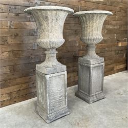 Pair of large Georgian design cast stone garden urns, egg and dart border, tapering column on square base, raised on square column