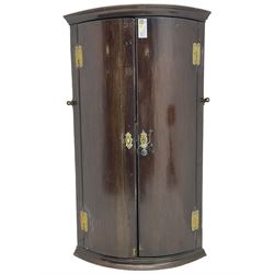 George III oak bow-front wall hanging corner cupboard, two doors enclosing four shaped shelves, brass hinges and escutcheons 
