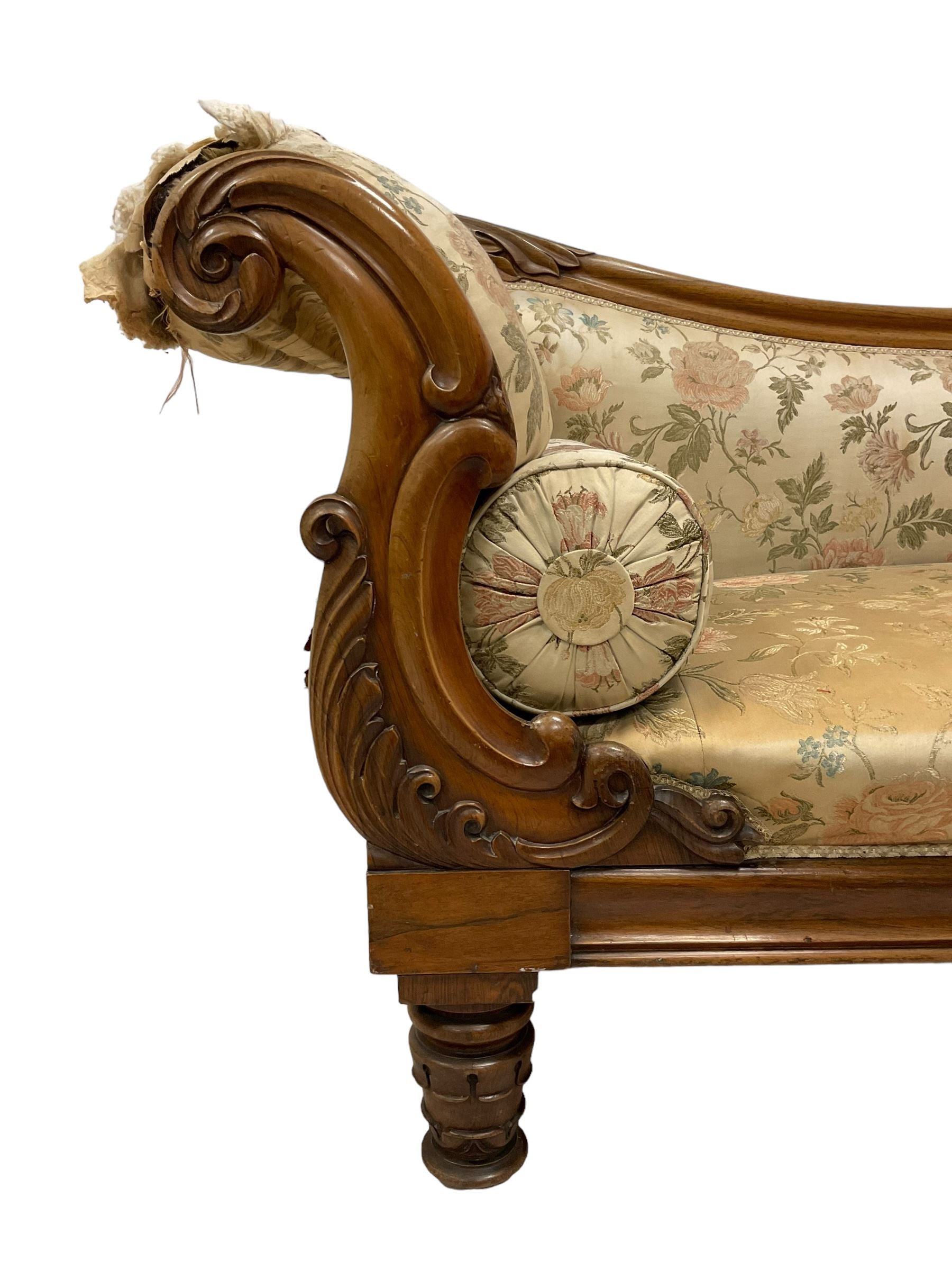 Victorian rosewood chaise longue, rolled back rest and shaped cresting rail carved with curled leaves and scrolls, upholstered in floral pattern fabric with bolster cushion, moulded lower rail with rectangular panel, on turned and lappet carved feet