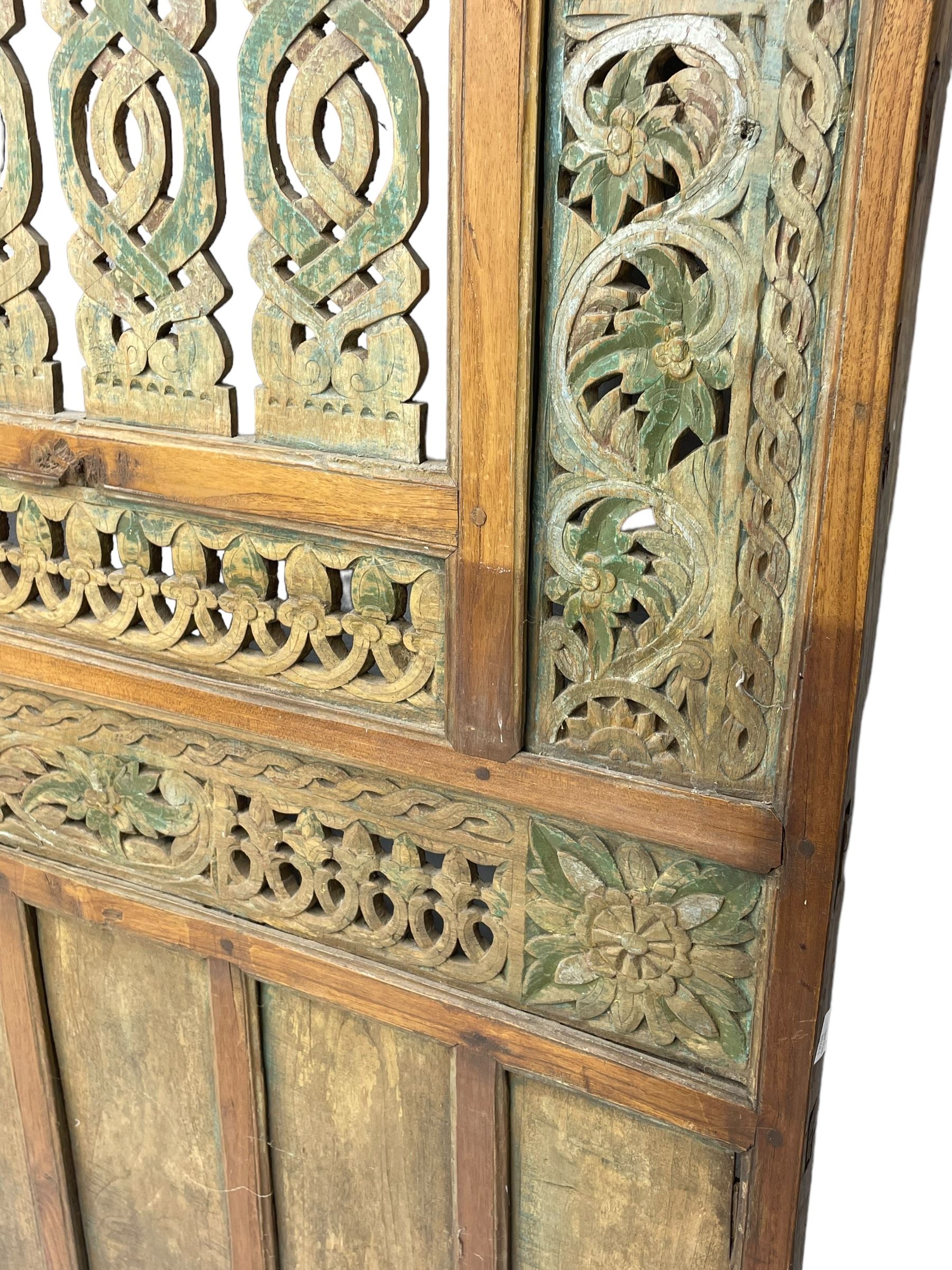 Early 20th century Javanese teak and hardwood door panel or room divider, rectangular panelled form with moulded frame and pegged construction, carved and pierced with scrolling decoration and flower head motifs, shaped and pierced splats with interlocking pattern