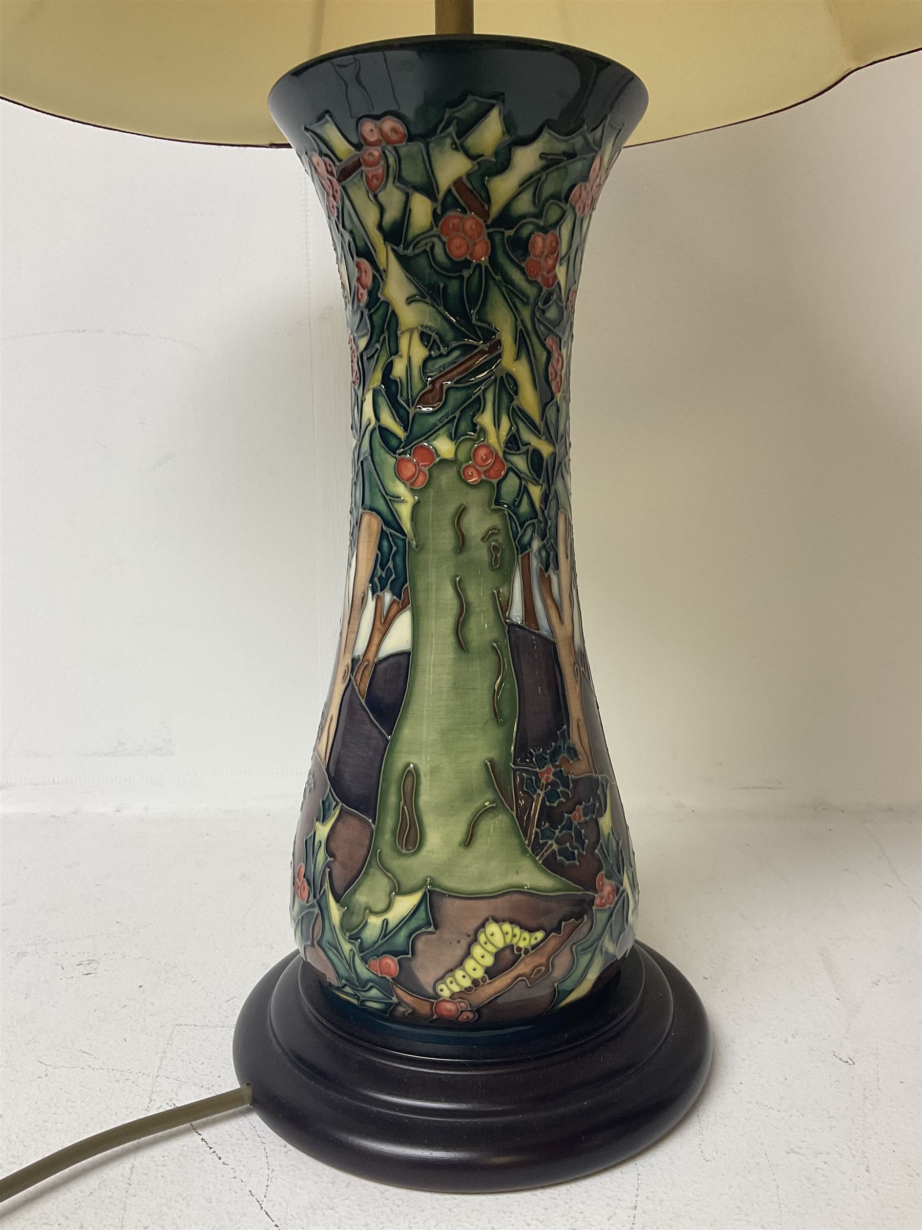 Moorcroft table lamp, of waisted form, decorated in the Holly Hatch pattern, on wooden plinth, with accompanying cream shade of lobed form, with piped detail, H33cm (excluding fitting)