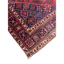 Persian Joshaghan red ground rug, the medallion, field and spandrels decorated with Pitrak and tree of life motifs, the border with repeating design decorated with stylised plant motifs, within guard stripes