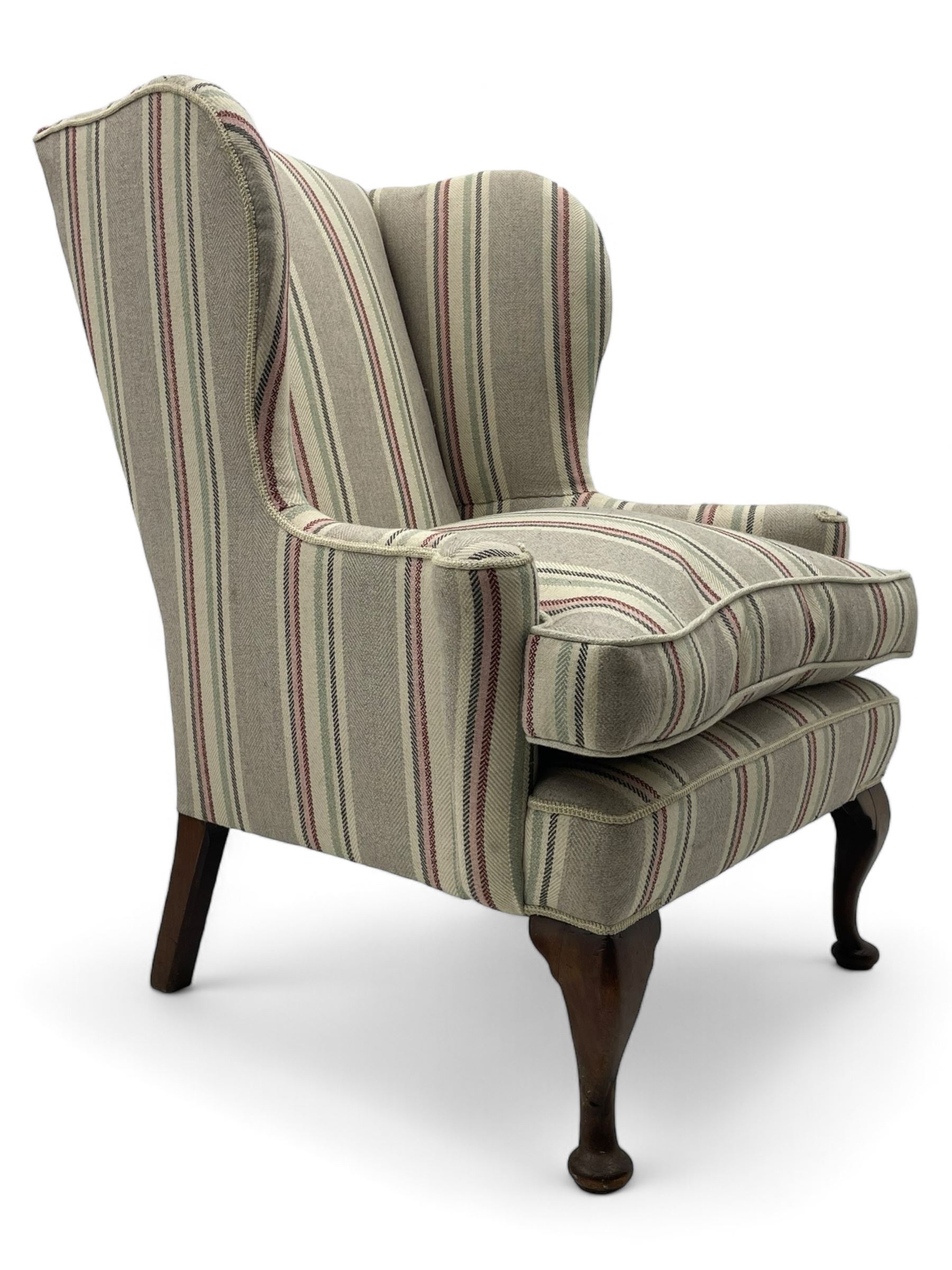 Georgian design hardwood-framed wingback armchair, curved wingback terminating to curved and rolled arms, upholstered in striped fabric with loose seat cushion, on cabriole front feet 