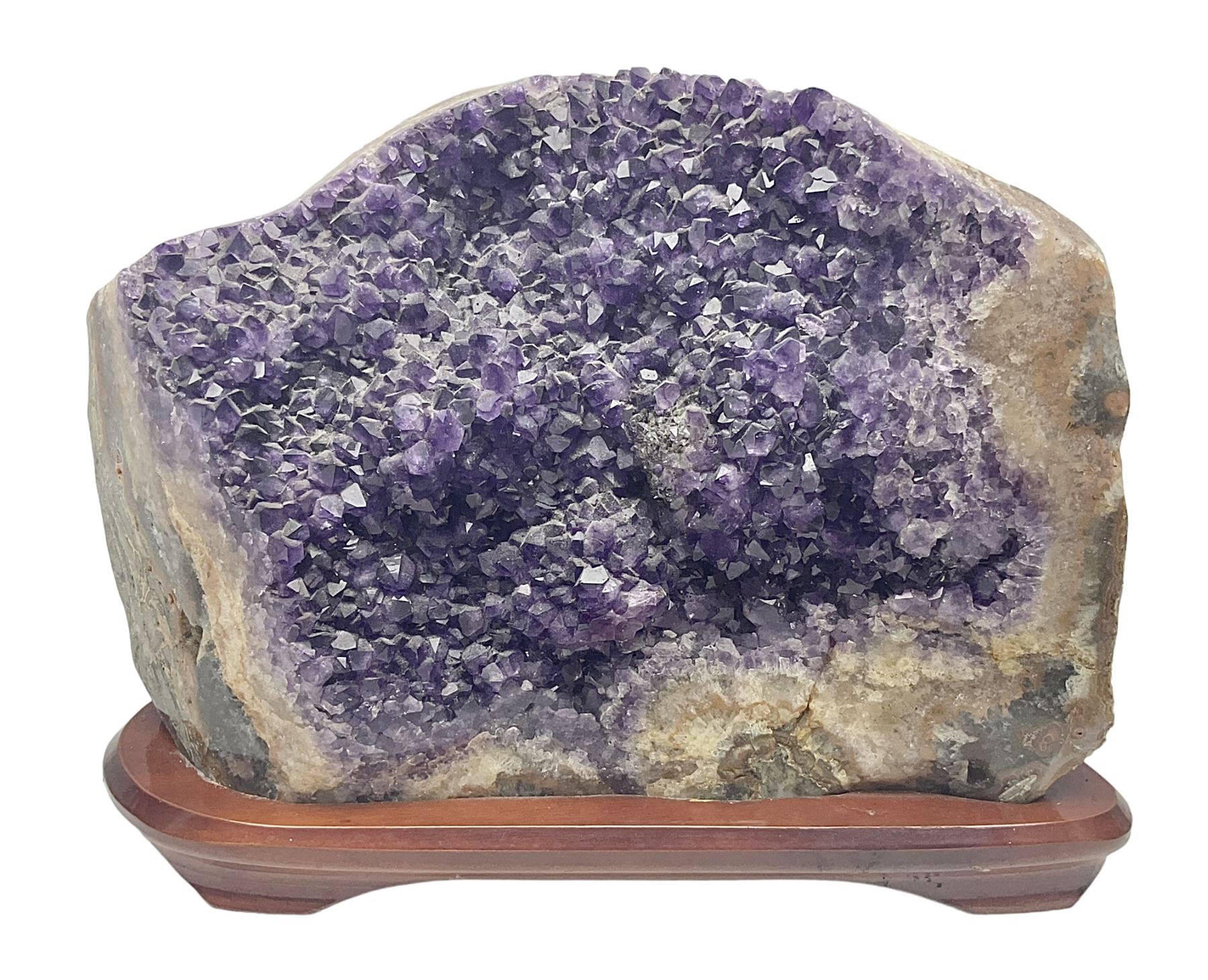 large amethyst crystal geode cluster, with well-defined crystals of various sizes, upon a carved wooden stand 